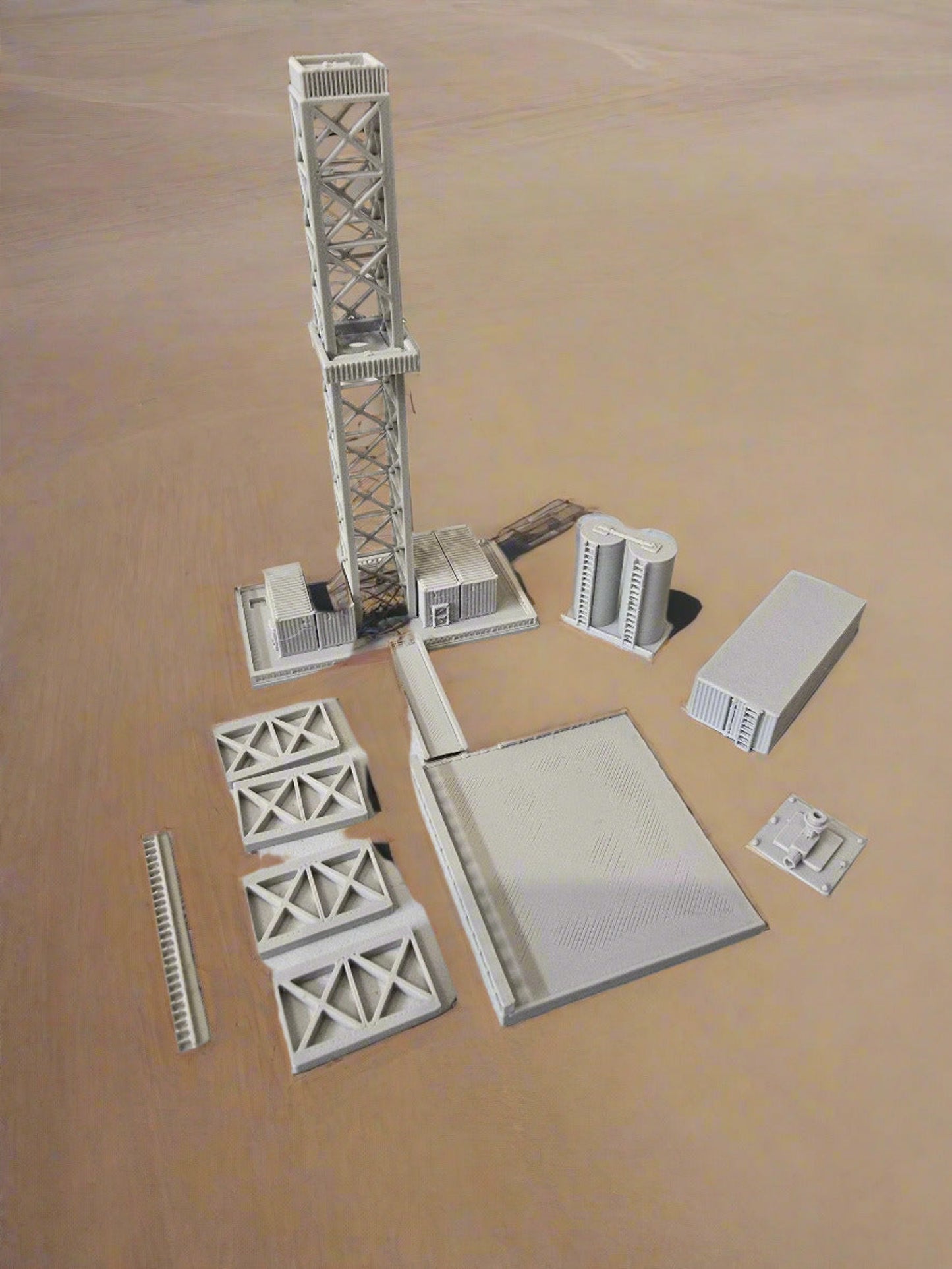 Model train tracks and infrastructure pieces on a light gray surface