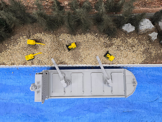 Model train track with a flatcar and small yellow cars on a blue platform.