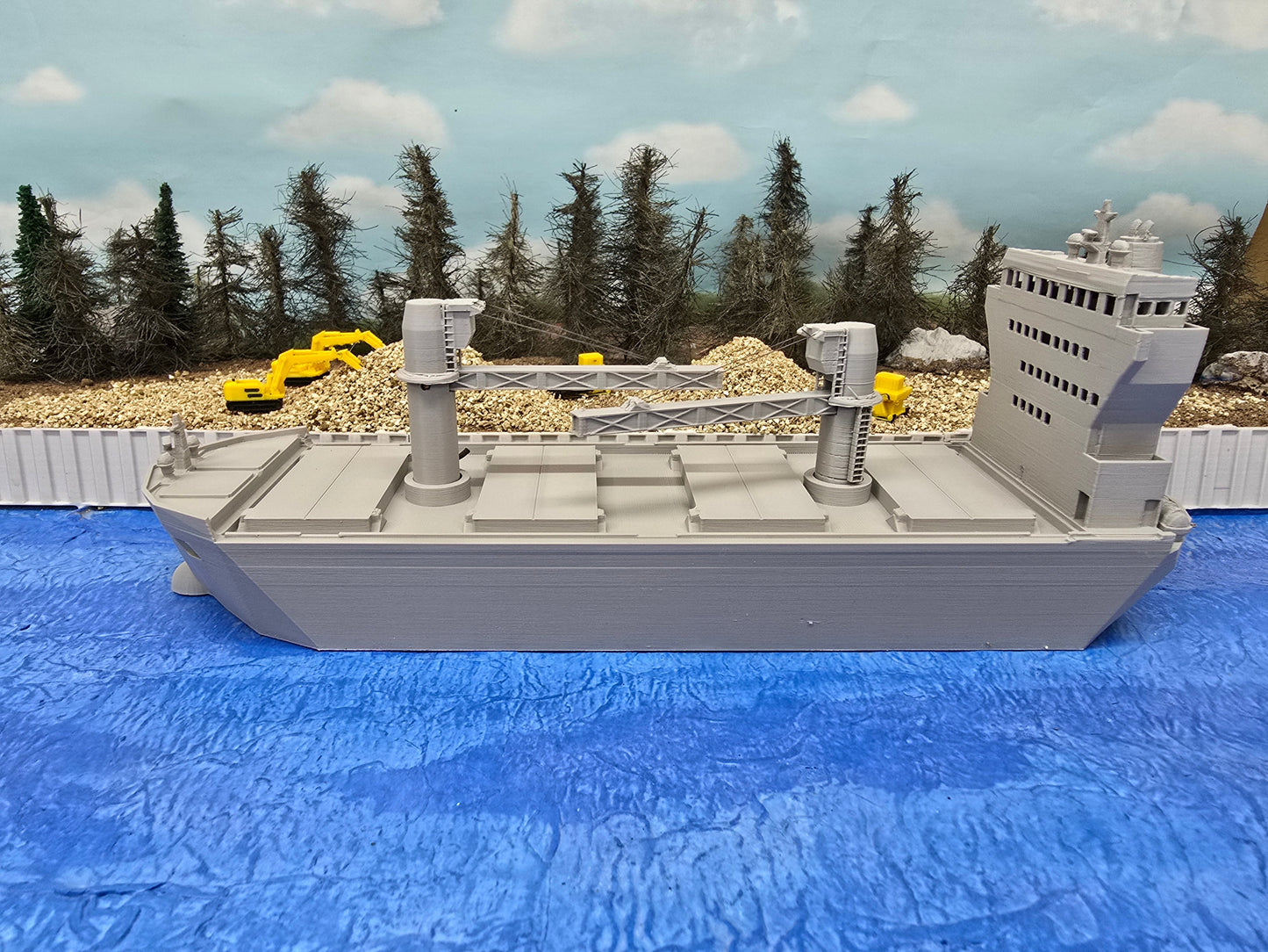 Model ship on a blue surface with a forest background