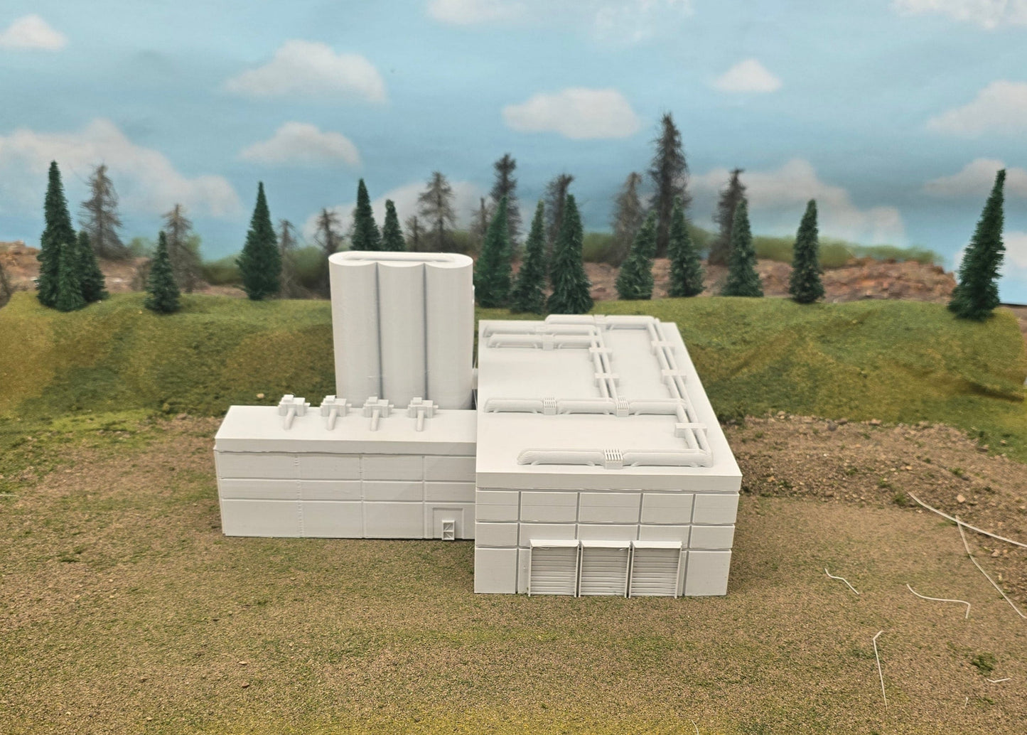 Model of a building with surrounding landscape and vehicles on a table