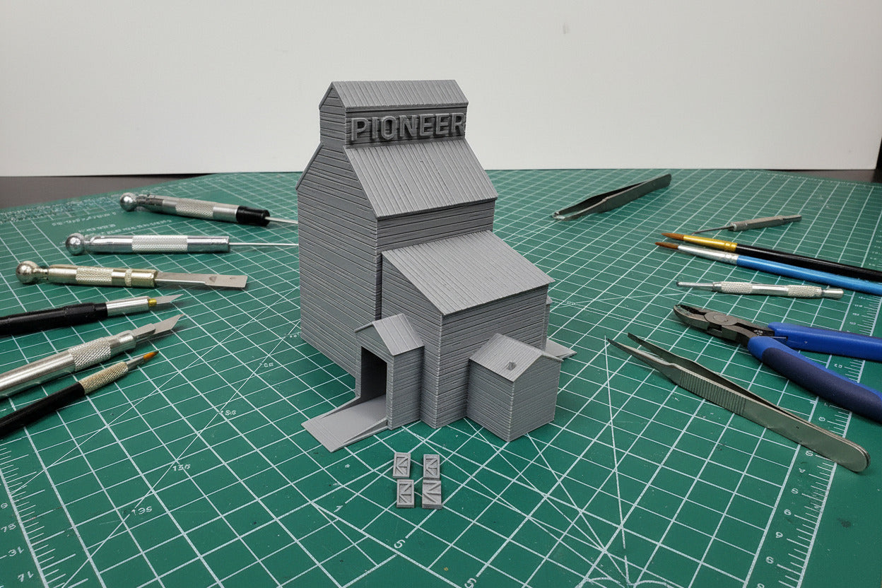 Model of a grain elevator with 'Pioneer' branding on a textured white surface.