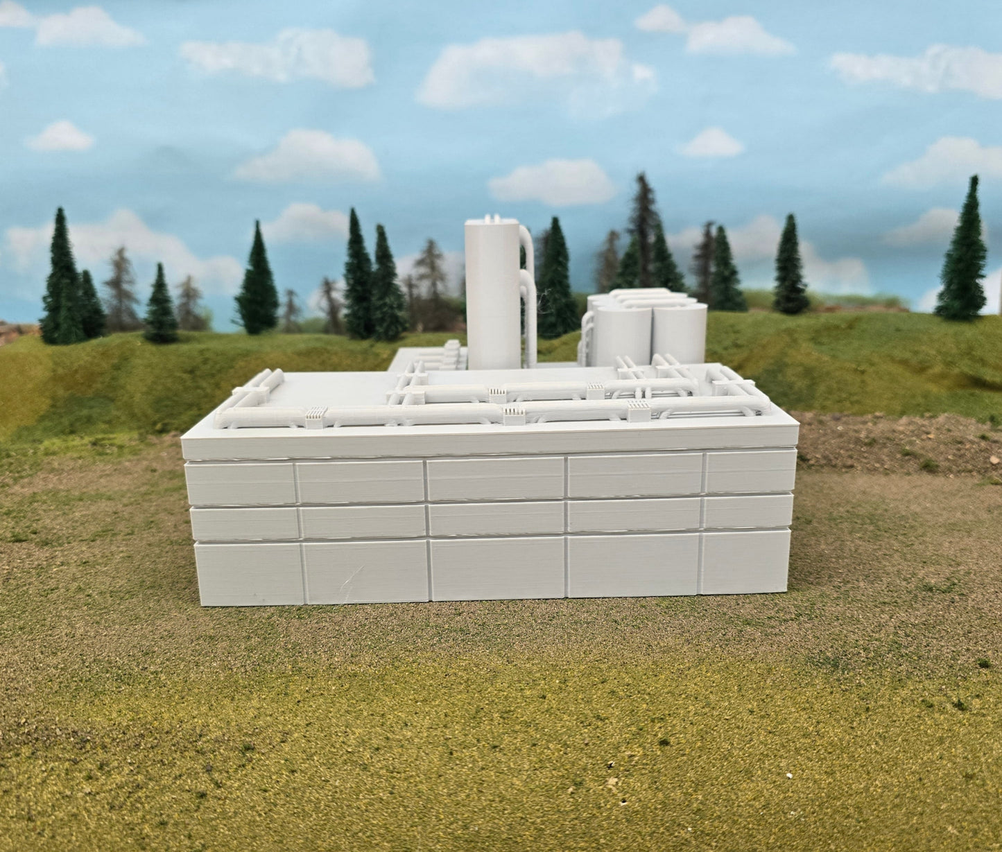 Model of a white building on a grassy area with trees and sky in the background