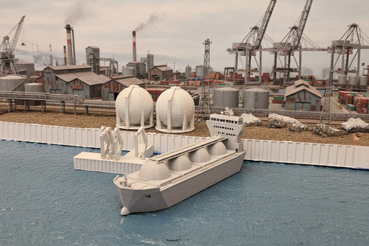 A Z scale model of an LNG transport ship with detailed structures and storage domes, placed on a model track with a backdrop depicting a calm sea and distant shores.