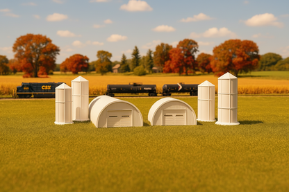 Model farm buildings and silos on a grassy field with a blue sky and clouds.