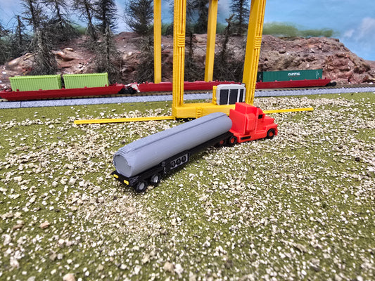 Model train set with red truck and gray tanker on a grassy track