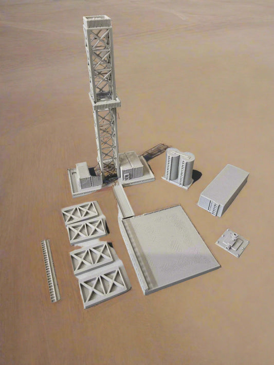Model train tracks and infrastructure pieces on a light gray surface