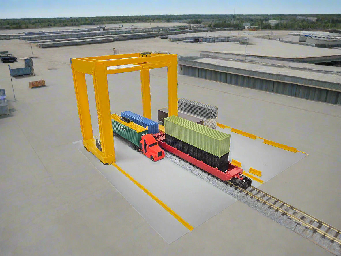 Model of a train passing under a yellow gantry crane on a white background