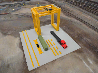 Model of a yellow crane and construction equipment on a gray platform with a white background