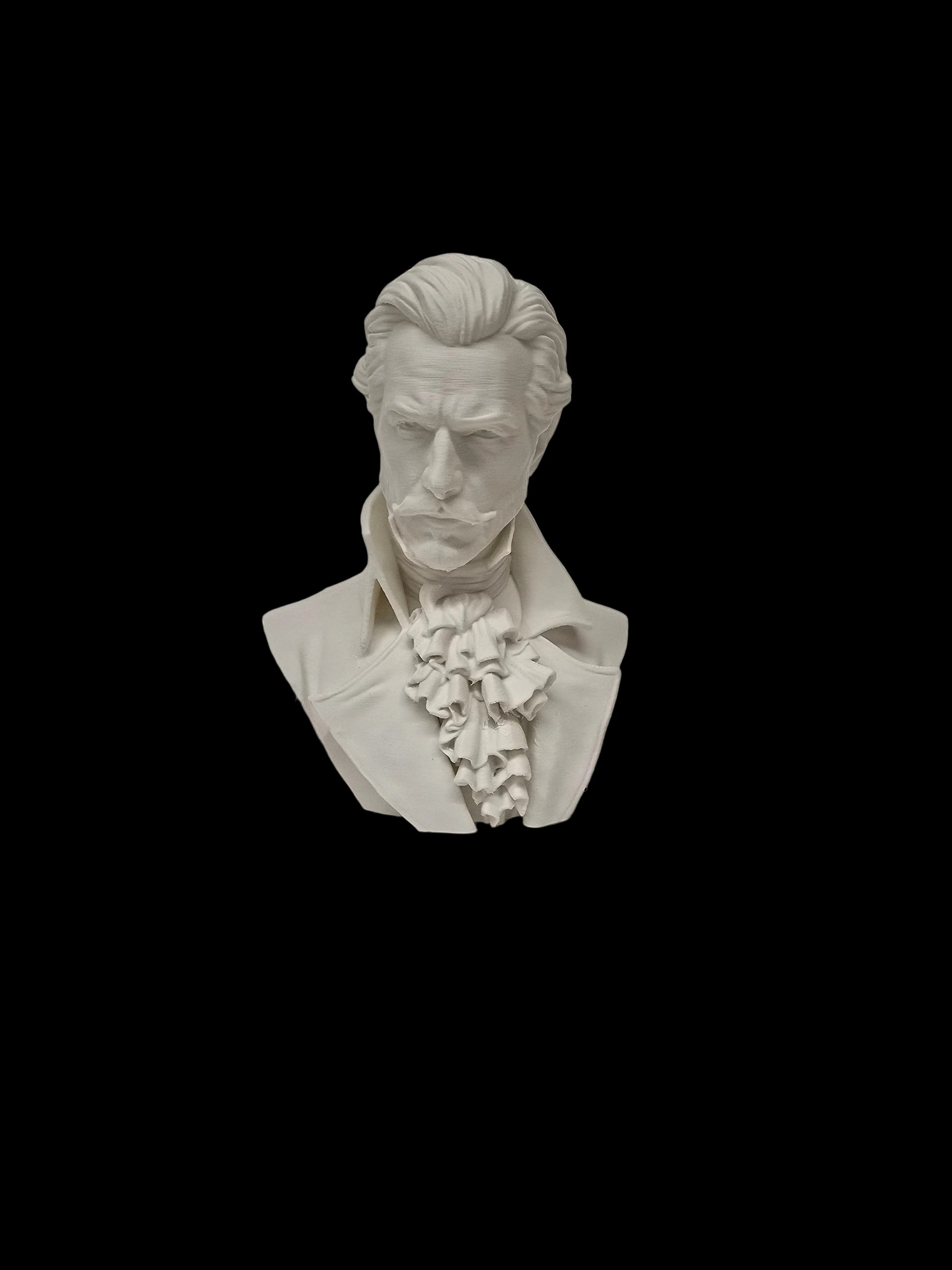 A white 3D-printed or resin miniature bust sculpture of a historical man with a high-collared shirt and ruffled cravat, standing on a textured white surface against a white wall.