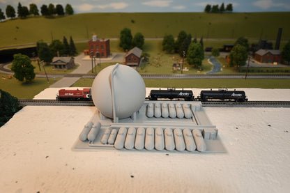 Model train set with a large round structure and two trains on a track.