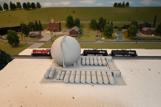 Model train set with a large round structure and two trains on a track.