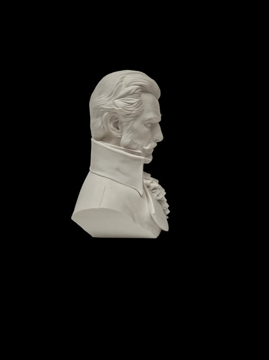 A white unglazed ceramic or plaster bust sculpture of a historical man in profile, shown on a textured white surface against a white wall.