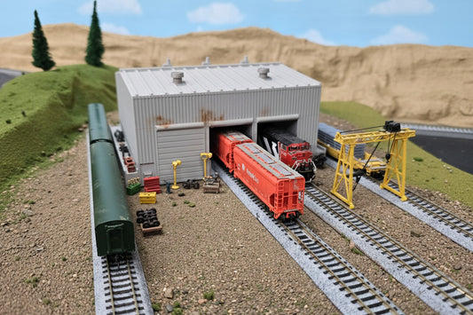 Model train set with a cargo train and station building on a track layout.