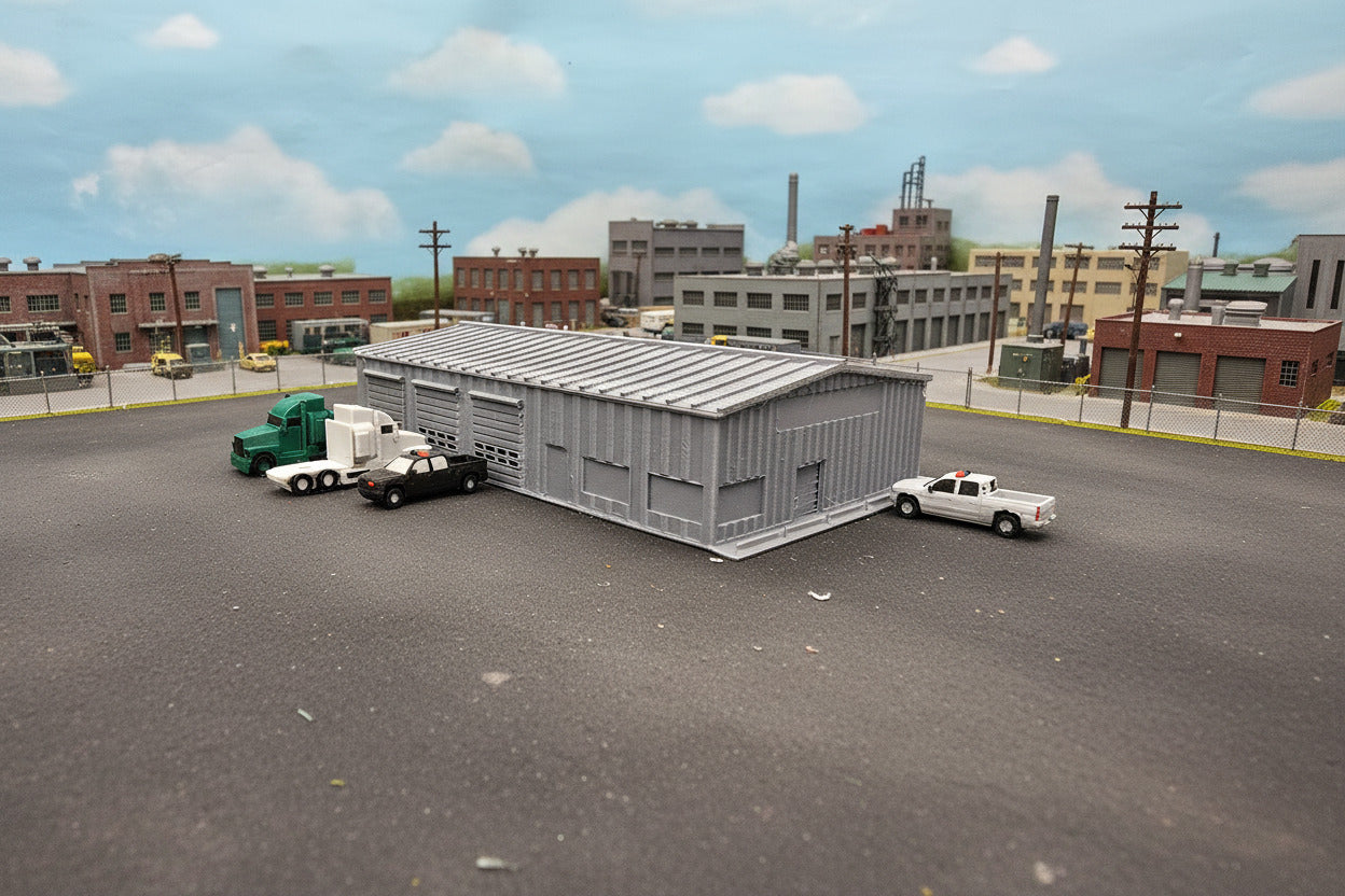 Model of a storage building with trucks and a car on a grassy field
