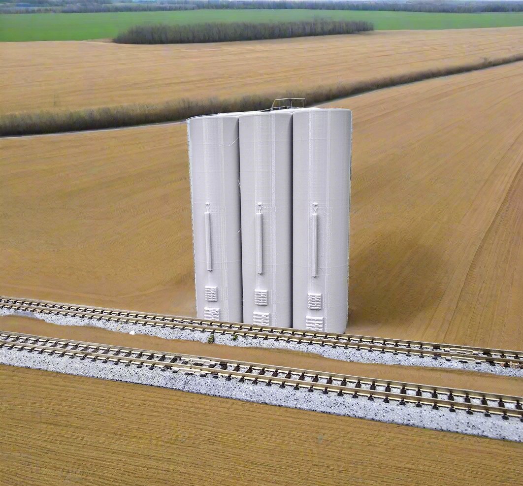 Z scale 3 Grain Trackside Elevators placed on a model train track surrounded by a field, depicting their use in a train layout.