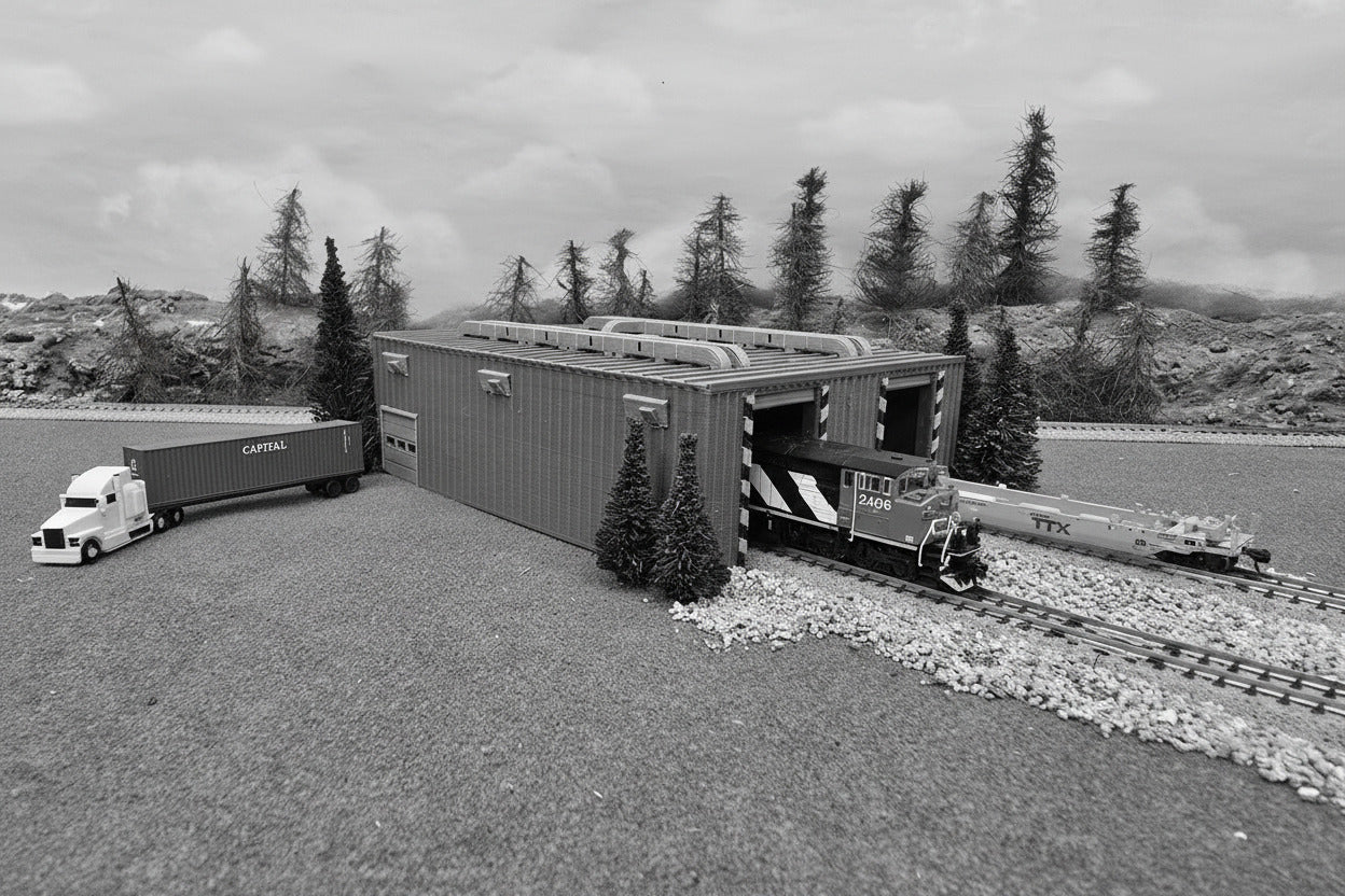 Model train set with blue cargo container, green truck, and trees in the background